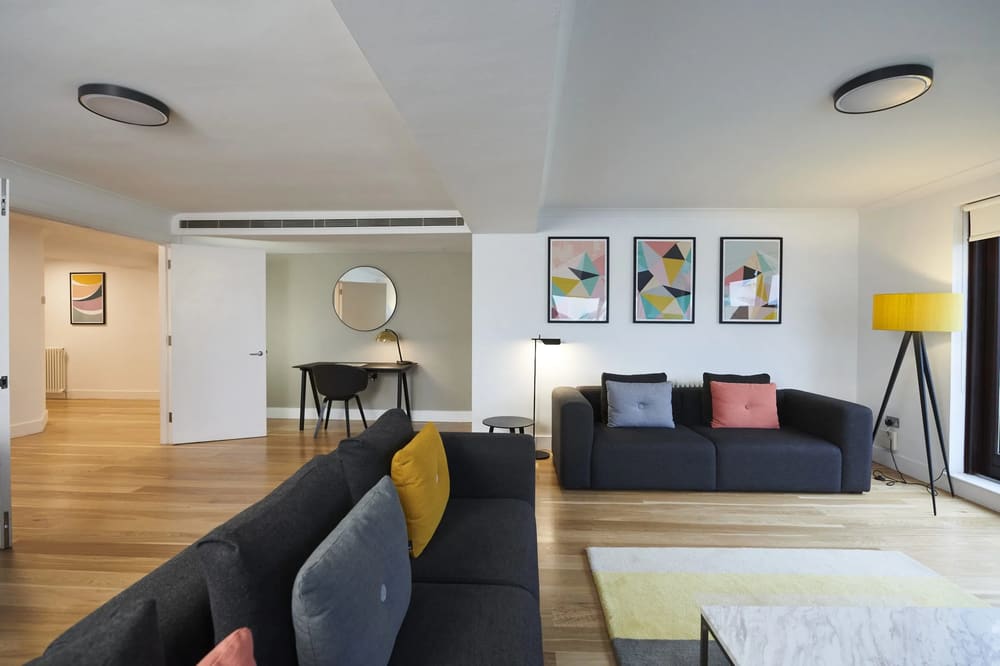 The Monarch Apartments, Kensington: Living room with dark sofa and colourful prints