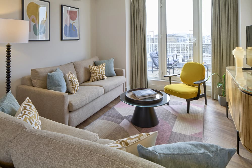 Cheval Harrington Court, Kensington: Living room with beige sofa and yellow armchair