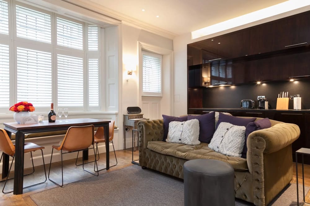 Prime Mayfair 1 bedroom no.2, W1K, Mayfair: Living room with olive Chesterfield sofa and open kitchen