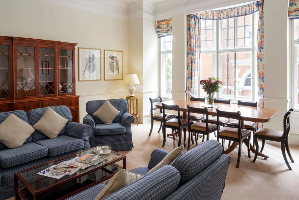 The Earls Court Road Apartments, Earl's Court: Living room with blue armchairs and dining table by bay window