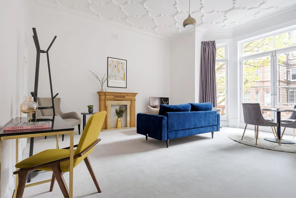 The Sloane Gardens Apartments, Chelsea: Living room with blue velvet sofa and fireplace