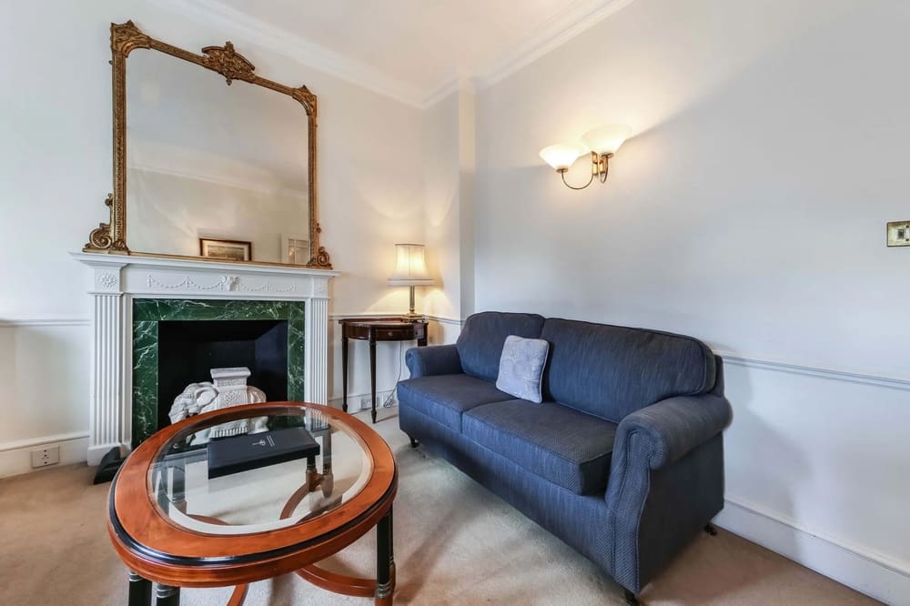 10 Curzon St, Mayfair: Living room with blue sofa, marble fireplace and gilt mirror