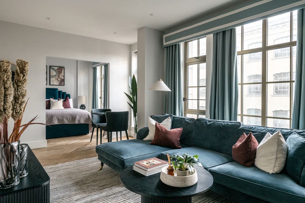 The Spitalfields Urban Rest Apartments, East London: Open-plan living room with teal sofa and bed area