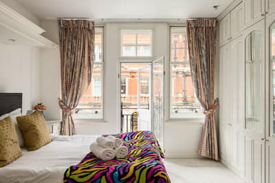 70 Duke Street Two Bedroom Apartment, Mayfair: Bedroom with patterned bedspread and tall windows