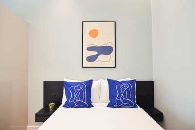 Earl’s Court East & West Apartments, Earl's Court: Double bed with blue cushions beneath framed print