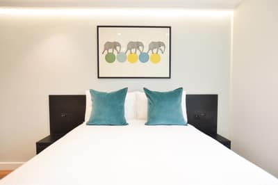 Earl’s Court East & West Apartments, Earl's Court: Bed with green cushions and bedside lighting