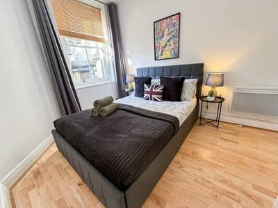 Hackney One Bedroom Apartment, East London: Bedroom with dark bed and tall curtained windows
