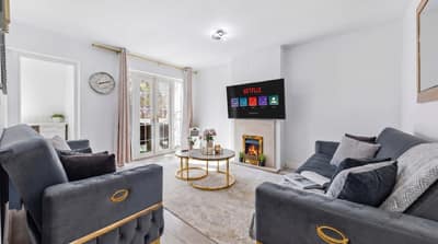 Marloes Road Two Bedroom Apartment, Kensington: Living room with dark sofas and glass table