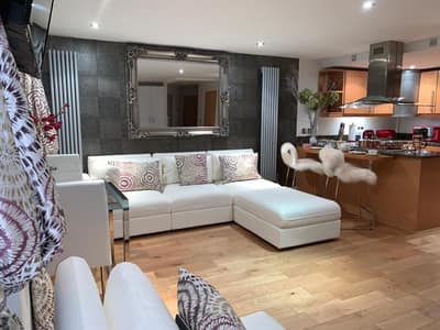 Millharbour One Bedroom Apartment, East London: Living space with pale sofa beside kitchen