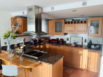 Millharbour One Bedroom Apartment, East London: Wooden kitchen cabinets beside fitted hob and oven
