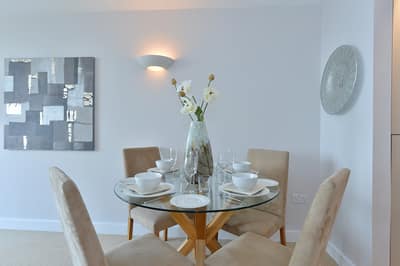 Neutron Tower One Bedroom Apartment, East London: Round glass dining table beside tall window