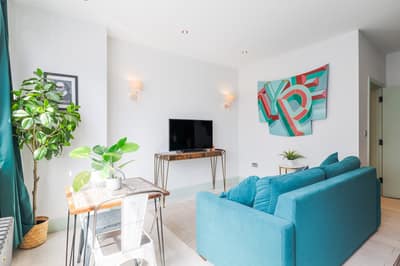 Noxley Newington Green One Bedroom, East London: Turquoise sofa beside dining table and artwork