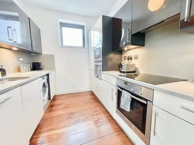 Pentonville Road Three Bedroom Apartment, King's Cross: Kitchen with white cabinets beside a window