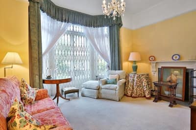 Sloane Gardens One Bedroom Apartment, Chelsea: Living room with fireplace and tall curtained window