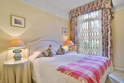 Sloane Gardens One Bedroom Apartment, Chelsea: Bedroom with patterned bedspread and bedside table