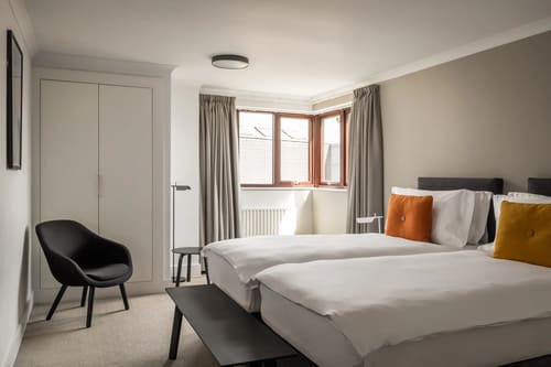 The Monarch Apartments, Kensington: Twin beds with orange cushion by a bay window