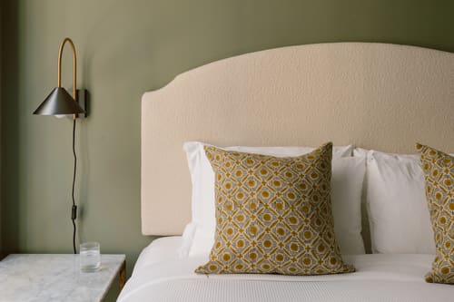 The St Paul’s Apartments, East London: Bed with cream headboard against green wall