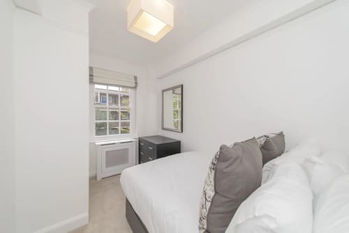 Chelsea Mansion Block, Chelsea: Bedroom with sash window and grey cushions