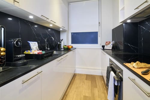 Cheval Harrington Court, Kensington: Kitchen with white units and black marble splashback