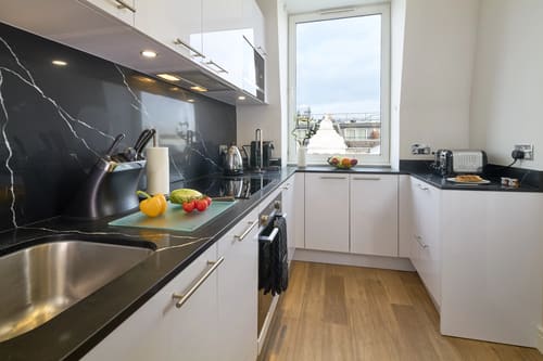 Cheval Harrington Court, Kensington: Kitchen with black worktop and window