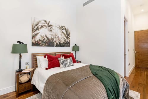 Hyde Park Gate Residences, Kensington: Double bedroom with red cushions and palm-print art