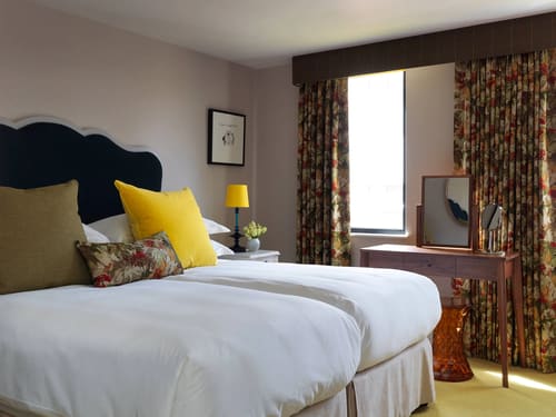 Cheval Knightsbridge, Knightsbridge: Twin beds with yellow cushions and patterned curtains