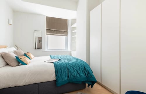 Royal Albert Apartments, Kensington: Bedroom with teal throw and fitted wardrobe