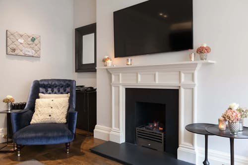Prime Mayfair 1 bedroom no.1, W1K, Mayfair: Fireplace with TV above and navy armchair