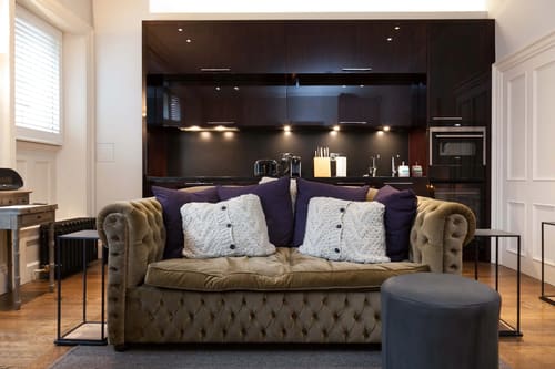 Prime Mayfair 1 bedroom no.2, W1K, Mayfair: Chesterfield sofa with dark kitchen behind