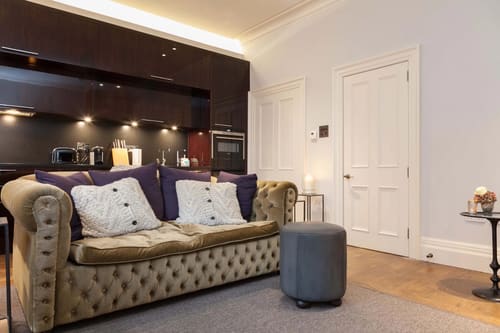 Prime Mayfair 1 bedroom no.2, W1K, Mayfair: Olive Chesterfield sofa with kitchen beyond