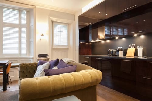 Prime Mayfair 1 bedroom no.2, W1K, Mayfair: Mustard Chesterfield sofa with kitchen beyond