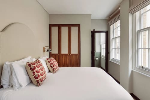 The St Paul’s Apartments, East London: Bedroom with red patterned cushions and sash window