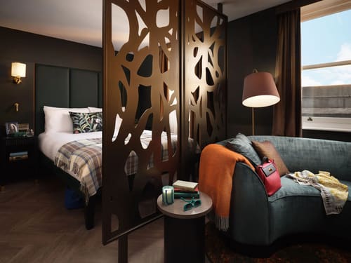 The Other House Apartments, Kensington: Bedroom with carved wooden screen and armchair