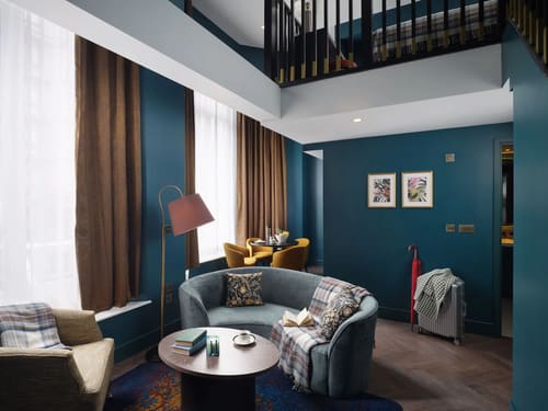 The Other House Apartments, Kensington: Living room with teal walls and curved grey sofa
