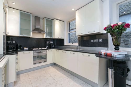 Nassau Street Chic, Fitzrovia: Kitchen with white units and black splashback