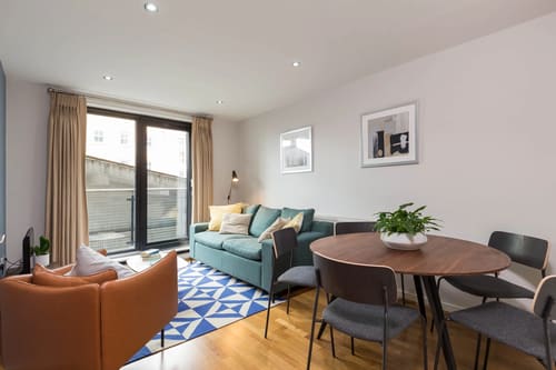 Waterloo Apartments, Waterloo: Living room with teal sofa and round dining table