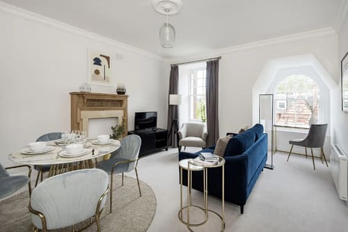 The Sloane Gardens Apartments, Chelsea: Living and dining room with fireplace and blue sofa