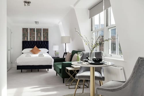 The Sloane Gardens Apartments, Chelsea: Studio with bed, dining table and green armchair