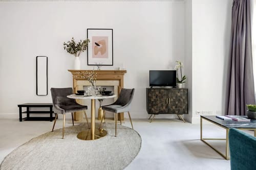 The Sloane Gardens Apartments, Chelsea: Round dining table beside a fireplace