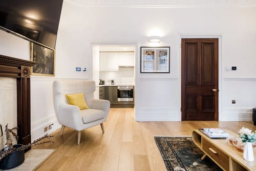 Mayfair 1 bedroom near Green Park, Mayfair: Living room with yellow armchair and panelled door
