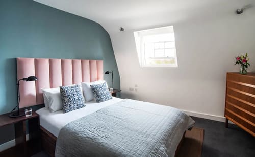 Lancaster Gate Apartments, Paddington: Bedroom with pink headboard under a sloping ceiling