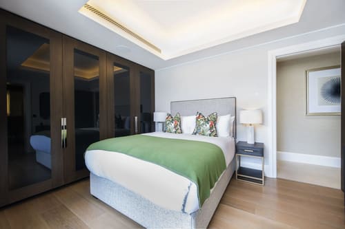Duke St, W1K, Mayfair: Bedroom with green throw and dark wardrobes