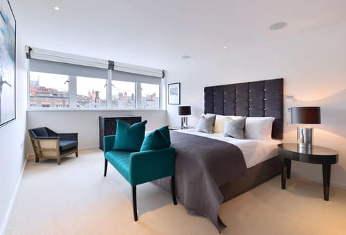 Kensington High St Apartments, Kensington: Bedroom with tall headboard and teal armchair