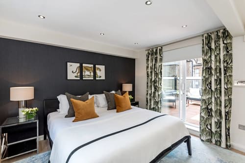 Hyde Park Gate, Kensington: Double bedroom with dark feature wall and mustard cushions