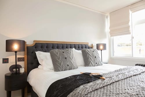 Prime Mayfair 2 bedroom, Mayfair: Bed with grey buttoned headboard and knitted cushions