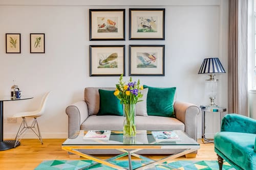 Nell Gwynn Chelsea Apartments, Kensington: Grey sofa with teal cushions beneath botanical prints