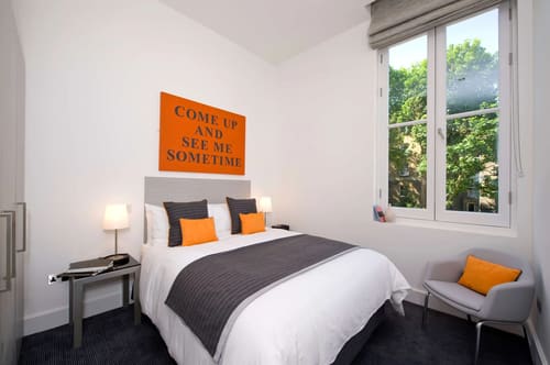 Templeton Place, Earl's Court: Double bedroom with orange cushions and neon-style sign