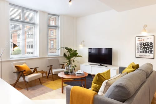Blandford Street Apartments, Marylebone: Living room with mustard cushions and TV unit