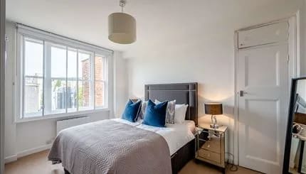 Hill St, W1K, Mayfair: Double bedroom with navy cushions and mirrored bedside table