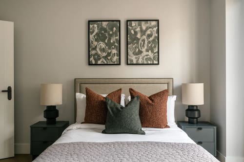 The Spitalfields Urban Rest Apartments, East London: Double bed with rust cushions and table lamps